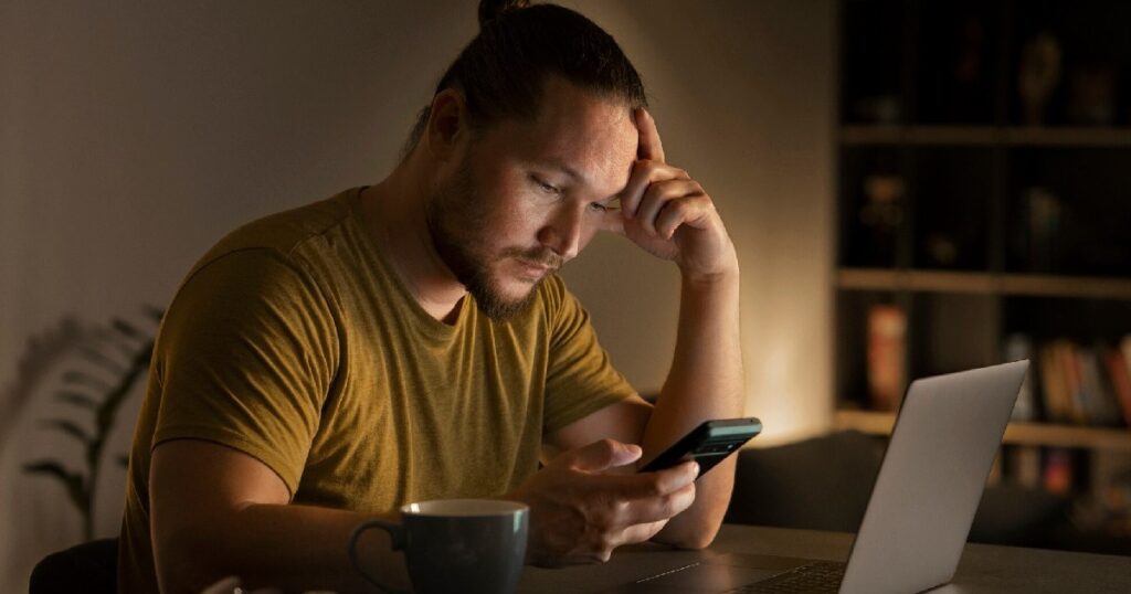 man staring at screens in need of digital detox with infrared sauna