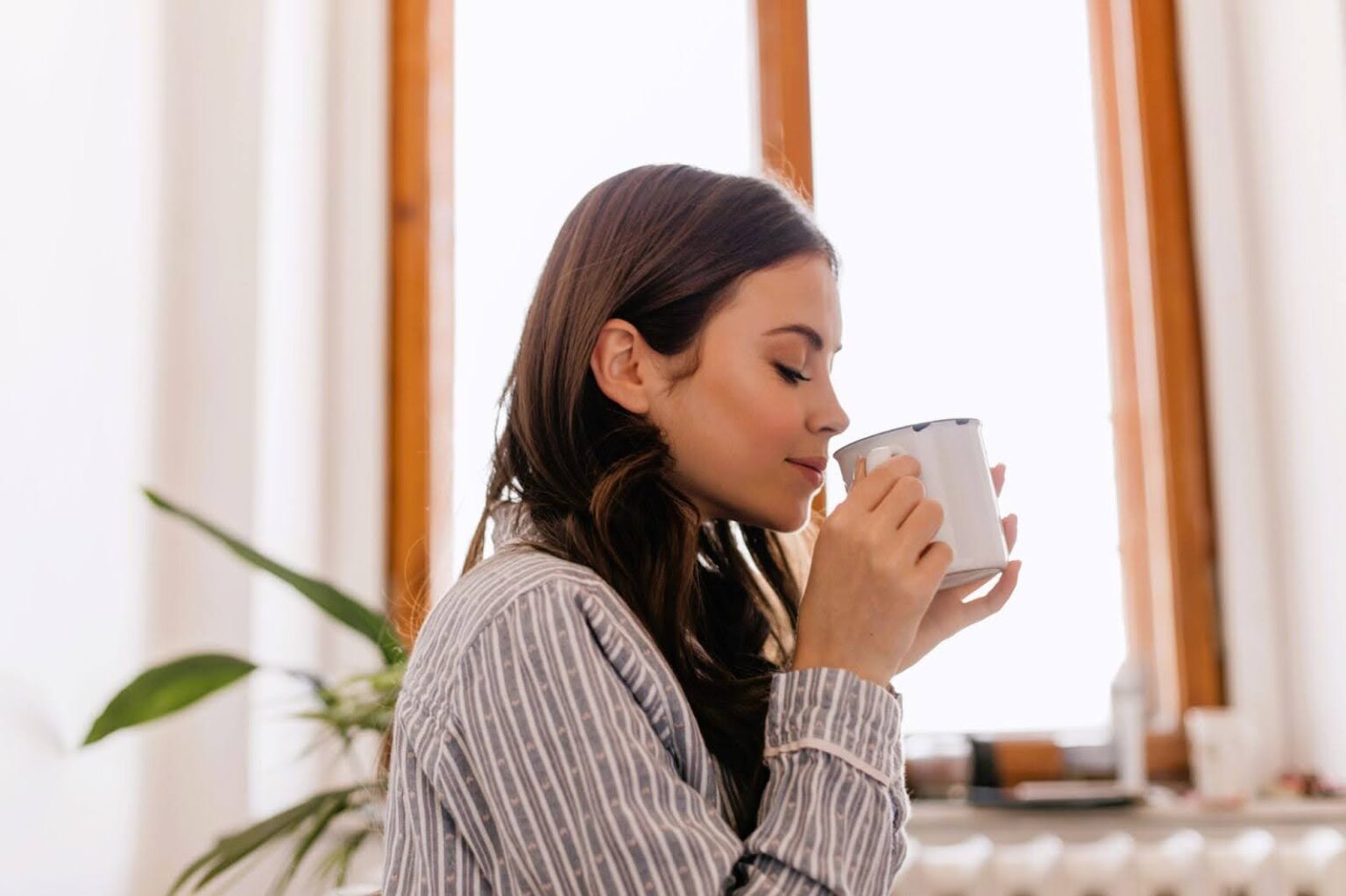 Woman enjoys coffee as part of morning routine that includes infrared sauna sessions